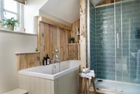 Modern country bathroom with wooden panelling on wall above bath