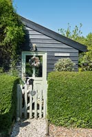 Pet dog at garden gate outside wooden country house 