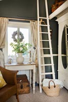 Tall white ladder against dark grey painted wall in country bedroom 