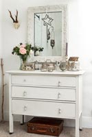 White painted wooden chest of drawers in country bedroom 