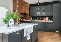Dark grey modern kitchen with exposed brick wall and parquet flooring 