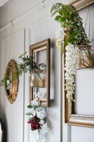 Vases of flowers suspended within empty gilded picture frames 