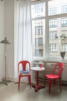 Bright red chairs and small side table next to window 