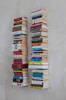 Tall towers of books on wall mounted floating shelves 
