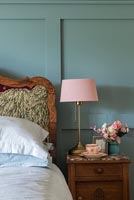 Pink lamp on bedside table next to green panelled wall 
