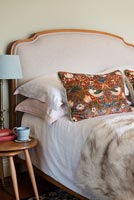 Pink headboard and patterned cushions on bed 