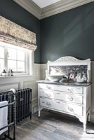Distressed white painted chest of drawers with sink in modern bathroom 