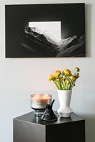 Flowers on side table with black and white picture above 