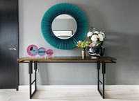 Display of decorative plates and flowers on modern console table 