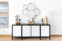Black and white sideboard and cluster of circular mirrors on wall 