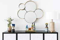 Black and white sideboard and cluster of circular mirrors on wall 