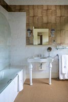 Country style bathroom with pedestal sink and natural flooring