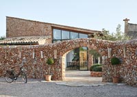 Archway in stone wall leading to modern country house