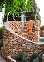 Outdoor shower set in curving stone wall 