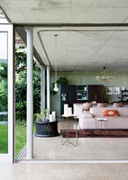 Open plan living space concrete walls and bifolding doors to garden