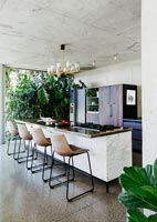 Contemporary dining area with concrete walls and bifolding doors to garden