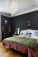 Pink and green bedspread in bedroom with black painted walls 