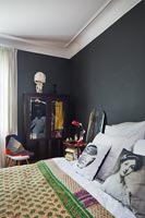 Pink and green bedspread in bedroom with black painted walls 