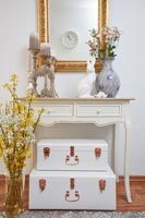 Suitcases under console table with Easter decorations and spring flowers 