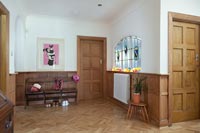 Hallway with wooden paneling and floor with seating area and stand glass window