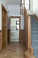 Hallway with wooden paneling and floor with open door leading to bathroom