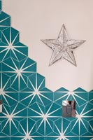 Star ornament on wall of bathroom with teal and white star patterned tiles 