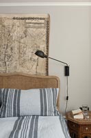 Rattan headboard in modern bedroom with ordinance map on wall