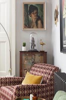 Patterned armchair and vintage ornaments in modern living room 