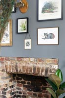 Display of framed artwork on grey painted wall above fireplace 