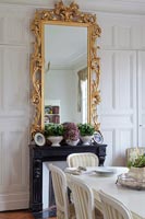 Gilded mirror on panelled wall in classic dining room 