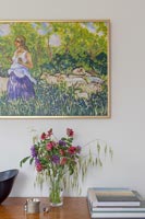 Purple and pink flower arrangement under colourful painting 