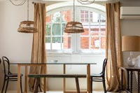 Wicker lampshades on pendant lights over dining table 