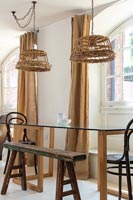 Wicker lampshades on pendant lights over dining table 