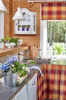 Country kitchen with checked fabric skirts on cupboards 