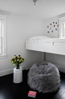 White bunkbed and furry floor cushion in modern childrens bedroom 