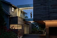 Person walking through glass link walkway - contemporary house exterior 