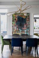 Large colourful artwork and unusual light over dining table 