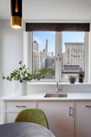 Modern kitchen with city skyline views through window 