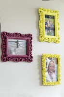 Family photographs in colourful frames on wall