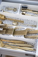 Detail of gold cutlery in kitchen drawer