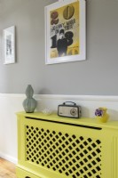 Vintage radio on yellow painted radiator cover in modern hallway
