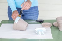 Using a brush to paint around the rim of the pot