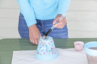 Spreading glue over the fabric on the base of the pot