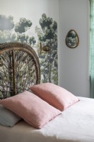 Painted mural behind bed with decorative wicker headboard