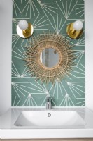 Sunburst mirror on patterned wall above bathroom sink