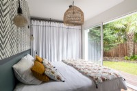 Modern bedroom with open patio doors to garden in summer 