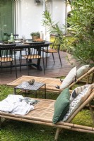 Bamboo recliners and outdoor dining area in small modern garden