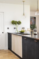 Modern country kitchen with dark cupboards, units, pendant lights, brass taps, double sink and wooden floors