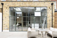 Exterior of brick kitchen extension with green crittall doors, windows.