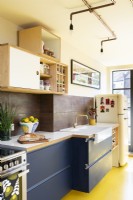 Modern retro kitchen with, yellow rubber floor, blue cabinets, plywood, copper pipe lighting
